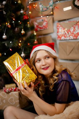 Noel kırmızı şapkalı mutlu kız. Hediyelerle süslenmiş yeni yıl ağacı 2020.