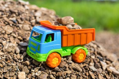çok renkli oyuncak kamyon kum ve taşların fonunda