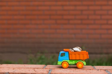 colored toy truck against a backdrop of sand stones clipart