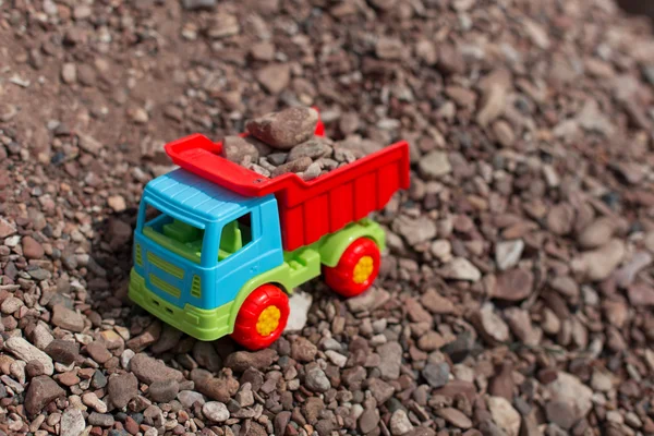 Camion jouet multicolore sur fond de sable et de pierres — Photo