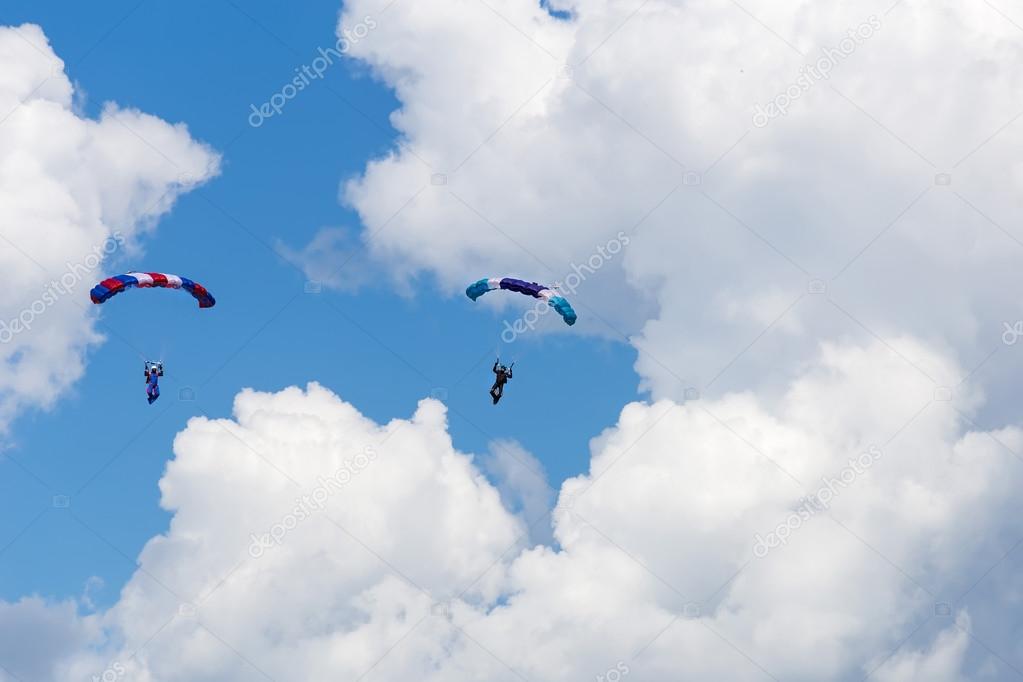 skydivers among the clouds and blue sky