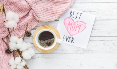 Güzel düz kompozisyon, fincan pamuk dalı ve beyaz ahşap arka planda kart. Anneler Günün kutlu olsun.