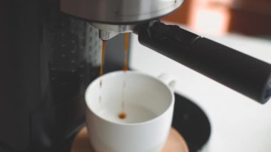 Kapuçino bardağının yakın çekimi. Kahve makinesi bir fincan kahveye espresso döker.