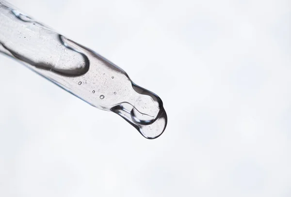 Druppel valt van een pipet in een cosmetische fles serum op witte achtergrond — Stockfoto