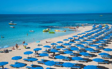 Plaj sandalyeleri ve kumsalda şemsiyeyle