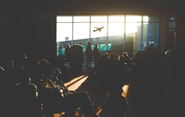 Havaalanında uçağa binmeyi bekleyen bir sürü yolcu var.