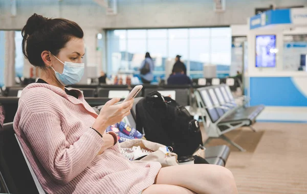 Kobieta w masce medycznej siedząca na lotnisku. koncepcja dystansu społecznego. Puste miejsca na lotnisku. Podróżując w czasie wirus Coonavirus, covid 19 pandemia — Zdjęcie stockowe