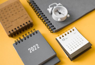 Takvimler 2022, not defteri ve alarm saati masanın üstünde. Yeni yıl kavramı