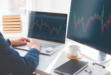 Yatırımcı, bilgisayar ekranlarındaki finansal panel, iş zekası ve anahtar performans göstergelerine sahip borsa yatırımlarını analiz ediyor