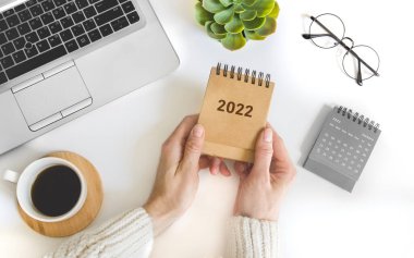Kadın el ele tutuşan masa takvimi. Gelecek yıl için 2022 Hedefin yapılacaklar listesi ve planları