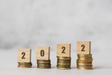 2022 yılının finansal planı. Bozuk paraların üzerinde tahta küpler, bütçe planlama kavramı.
