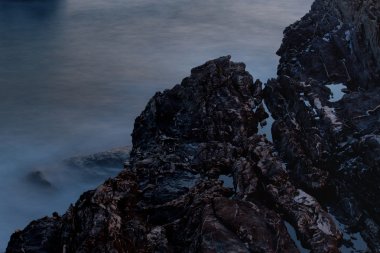 Gece denizde kayalarla