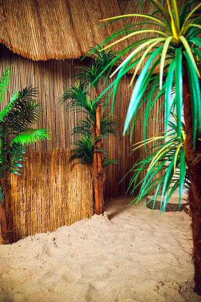 Kum ve palmiye ağaçları ile thatched kulübe