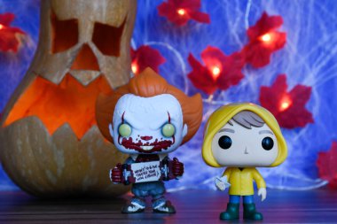 Pennywise Palyaçosu ve korku filmi It 'ten Georgie' nin aksiyon figürleri. Cadılar Bayramı dekor, Jack o fener, örümcek ağı, yapraklar, ışıklar.