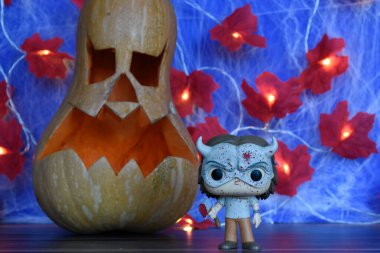 Korku filmi The Black Phone 'daki seri katil Grabber' ın aksiyon figürü. Cadılar Bayramı dekor, Jack o fener, örümcek ağı, yapraklar, ışıklar.