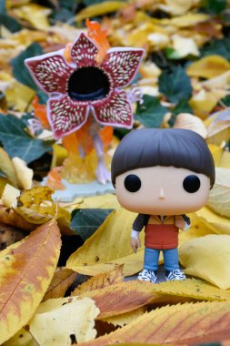Popüler TV dizisi Stranger Things 'ten Will Byers ve canavar Demogorgon' un Funko Pop aksiyon figürleri. Ormanda sonbahar yaprakları.