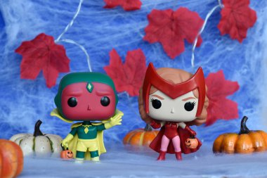 Marvel süper kahramanları Kırmızı Cadı Wanda ve Vizyon 'un Cadılar Bayramı kostümlü Funko Pop aksiyon figürleri. Örümcek ağı, kırmızı yapraklar, balkabakları, mavi sis manzarası.