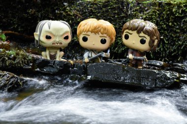 Gollum, Sam ve Frodo 'nun Yüzüklerin Efendisi filmindeki Funko Pop aksiyon figürleri. Yosunlu ıslak taşlar, köpüklü su.