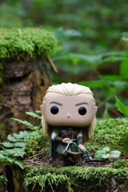 Fantezi filmi Yüzüklerin Efendisi 'ndeki Elf Legolas' ın aksiyon figürü. Ok ve yay tutan savaşçı. Yeşil orman, yosun, eğreltiotu yaprakları.