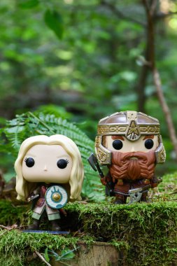 Cüce Gimli ve fantezi filmi Yüzüklerin Efendisi 'ndeki Eowyn' in aksiyon figürleri. Yeşil orman, yosun, eğreltiotu yaprakları.
