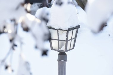 Kalın kabarık kar tabakasıyla kaplı klasik sokak lambası. Kış bahçesinin estetik detayları.