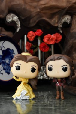 Funko Pop action figures of princess Belle from Disney animated film Beauty and the Beast and popular tv series Once upon a time. Fabulous palace, red roses.