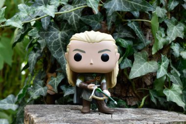 Fantezi filmi Yüzüklerin Efendisi 'ndeki Elf Legolas' ın aksiyon figürü. Ok ve yay tutan savaşçı. Gizemli ormanlık, sarmaşık yaprakları, yeşil orman.