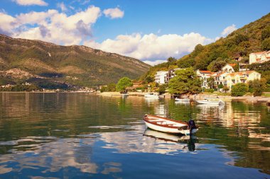 Güneşli bir sonbahar günü. Güzel Akdeniz manzarası, bulutlar ve dağlar suya yansıyor. Karadağ, Adriyatik Denizi, Kotor Körfezi, Tivat, Donja Lastva köyü manzaralı