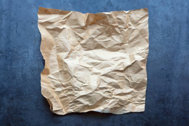 Metalik zemin üzerine buruşmuş eski kağıt parçası.