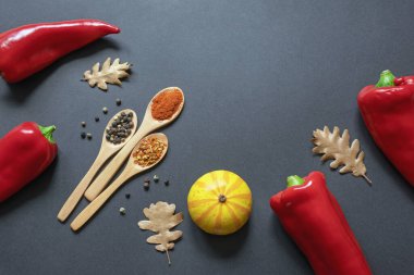 Sonbahar. Kırmızı biber, balkabağı, sonbahar yaprakları. Ahşap kaşıklarda biber baharatı. Düz yat, boşluğu kopyala