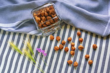 Fındık. Küçük bir kavanozdaki fındık çekirdekleri çizgili bir masa örtüsünün arka planında.