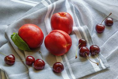 Kırmızı yaz meyveleri. Masada taze kiraz ve nektarin var.