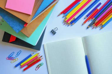 Bir yığın ders kitabı, açık çalışma kitabı ve renkli kalemler. Okula dönelim. Boşluğu kopyala