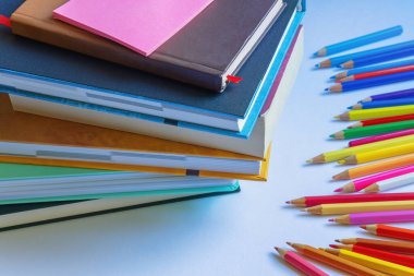 Masada bir yığın ders kitabı ve renkli kalemler var. Seçici odak