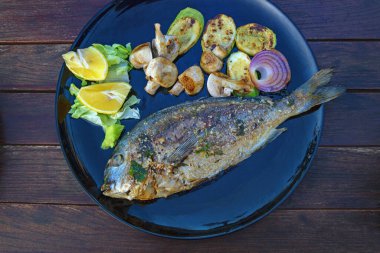 Kırsal masada siyah tabakta sebzeli ızgara balık çorbası. Balkan mutfağı, sağlıklı yiyecekler