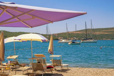 Yaz tatili. Karadağ, Kotor Körfezi, Tivat. Şezlongları ve plaj şemsiyeleri olan plaj.