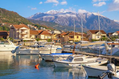 Limanda balıkçı tekneleri. Güneşli kış gününde Akdeniz manzarası. Karadağ. Tivat 'taki Kalimanj marinasının manzarası. Karla kaplı Lovcen Dağı