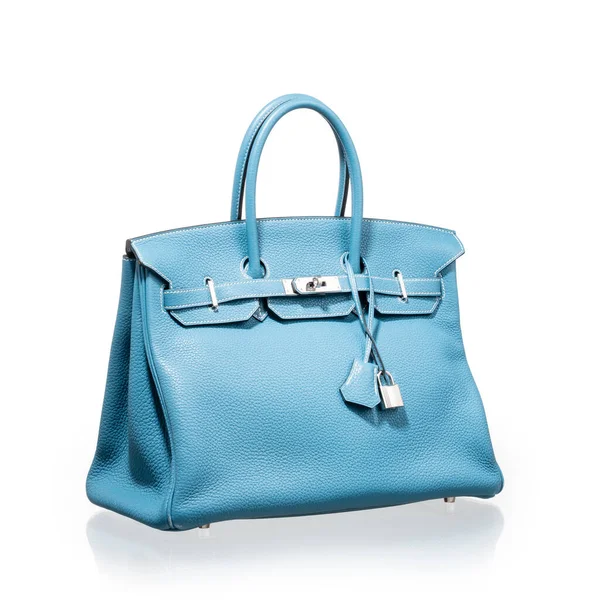 Modern mavi deri çanta, beyaz arka planda yansıması ile fotoğraflanmış.