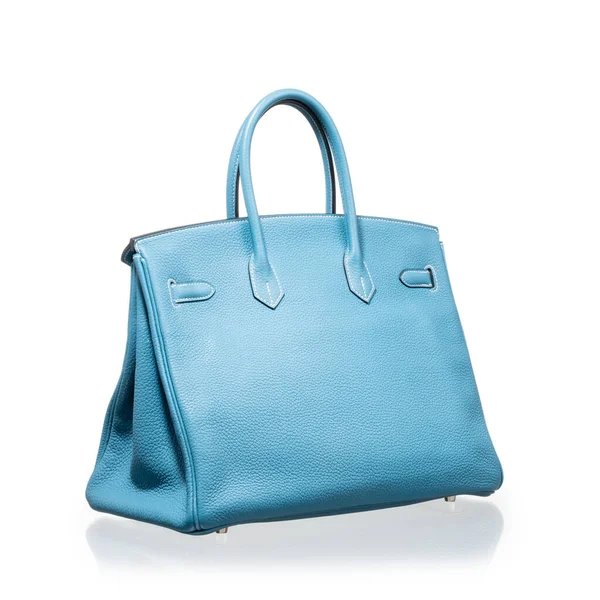 Modern mavi deri çanta, beyaz arka planda yansıması ile fotoğraflanmış.