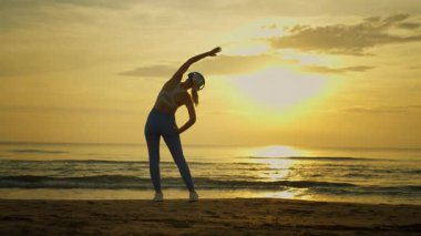 Sahilde yoga yapan bir kadın.