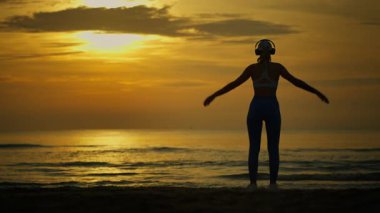 Genç kadın plajda yoga yapıyor.