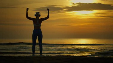 Genç adam gün batımında sahilde koşuyor.