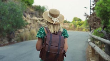 Sırt çantalı genç bir kadın yolda yürüyor.