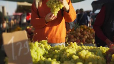 Elinde olgun kırmızı üzümlerle dolu bir sepet tutan bir kadın.