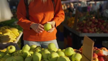 Süpermarkette elinde bir sepet taze elmayla bir kadın.