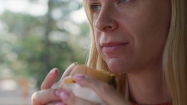 Kafede sandviç yiyen bir kadın.