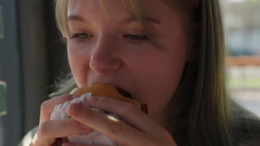 Patates kızartmasıyla sandviç yiyen güzel bir kadın..