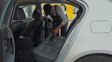 Araba sürücüsü arabanın kapısına emniyet kemeri takıyor.