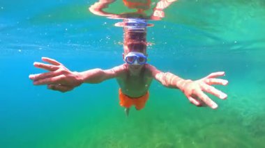 Mutlu genç çocuk denizin altında şnorkelle yüzüyor.