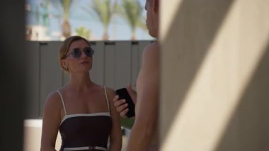 Kadın mayo giymiş, kocasıyla havuzda.